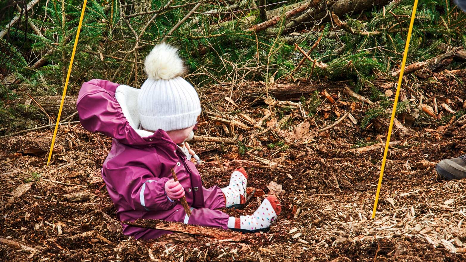 Kleines Kind sitzt auf einem Waldboden