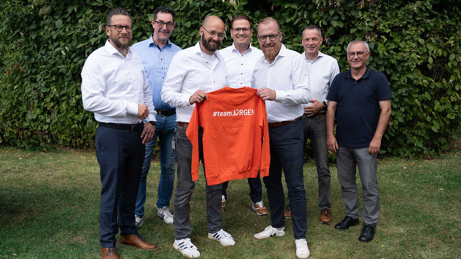 Gruppenbild der Geschäftsführer der Stadtwerkenergie, zwei Personen halten einen orangen Pullover mit Aufschrift #teamJÜRGEN