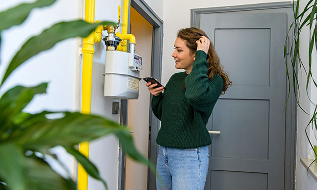 Frau liest einen Gaszähler ab