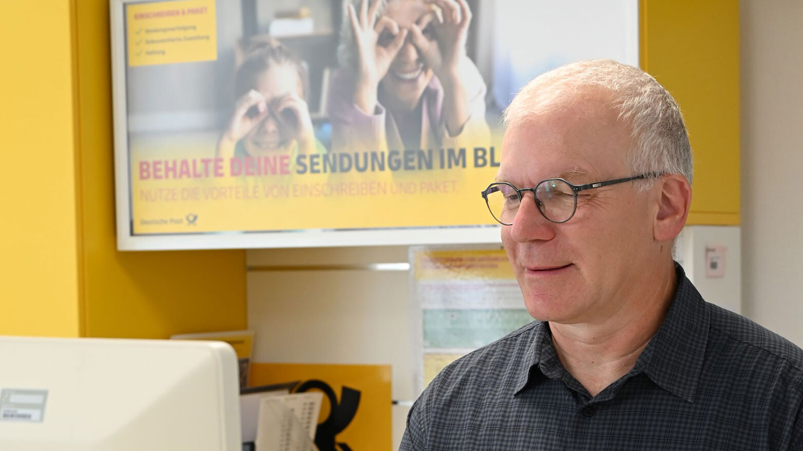 Mann lehnt an Briefkästen und liest einen Brief
