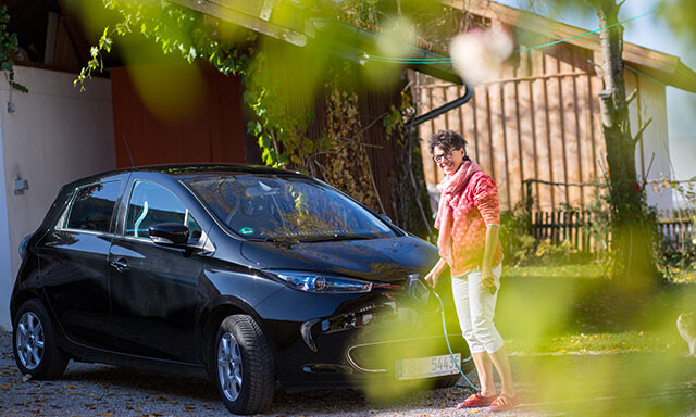 Frau lädt ihr Elektrofahrzeug an einer Wallbox